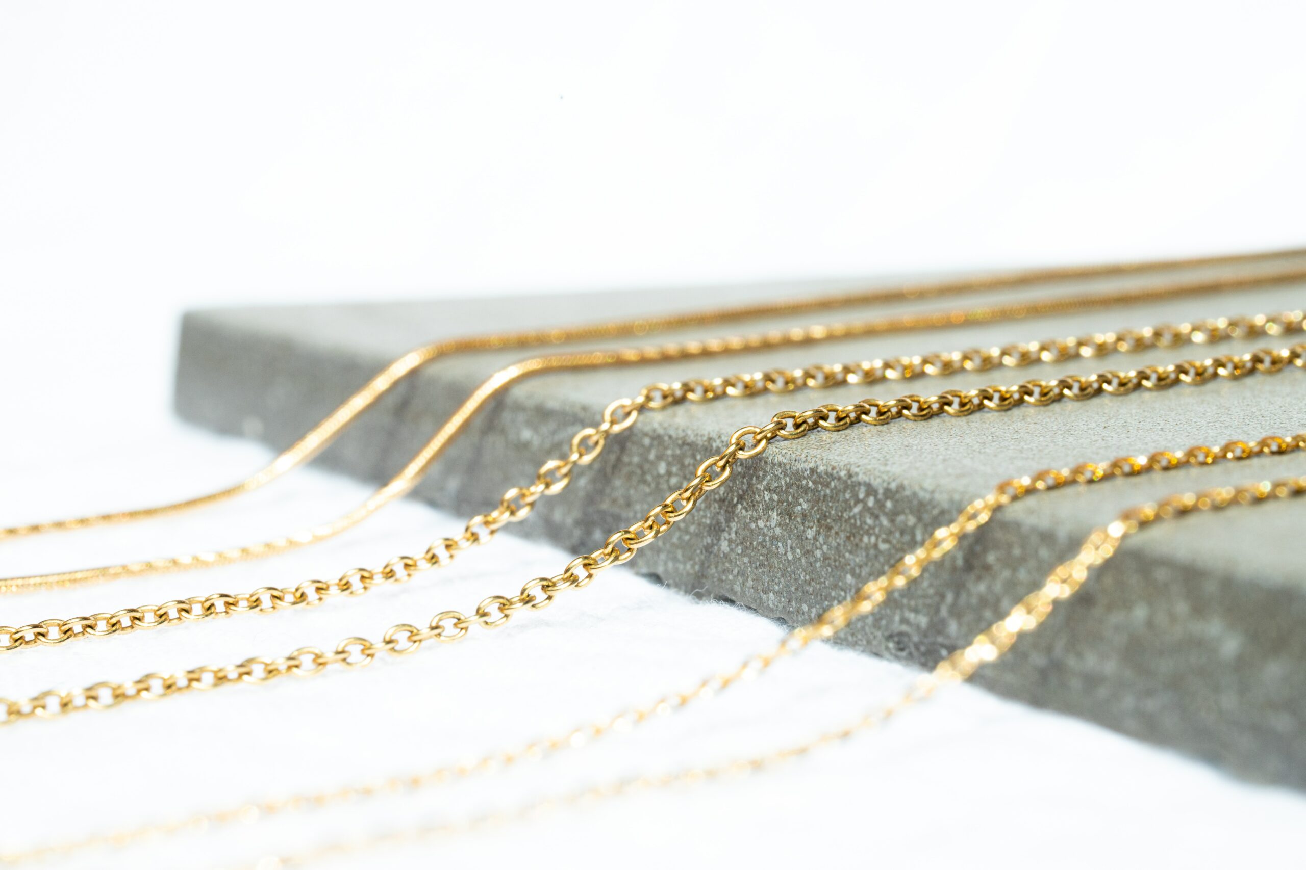 Various textures and sizes of gold chain on display.