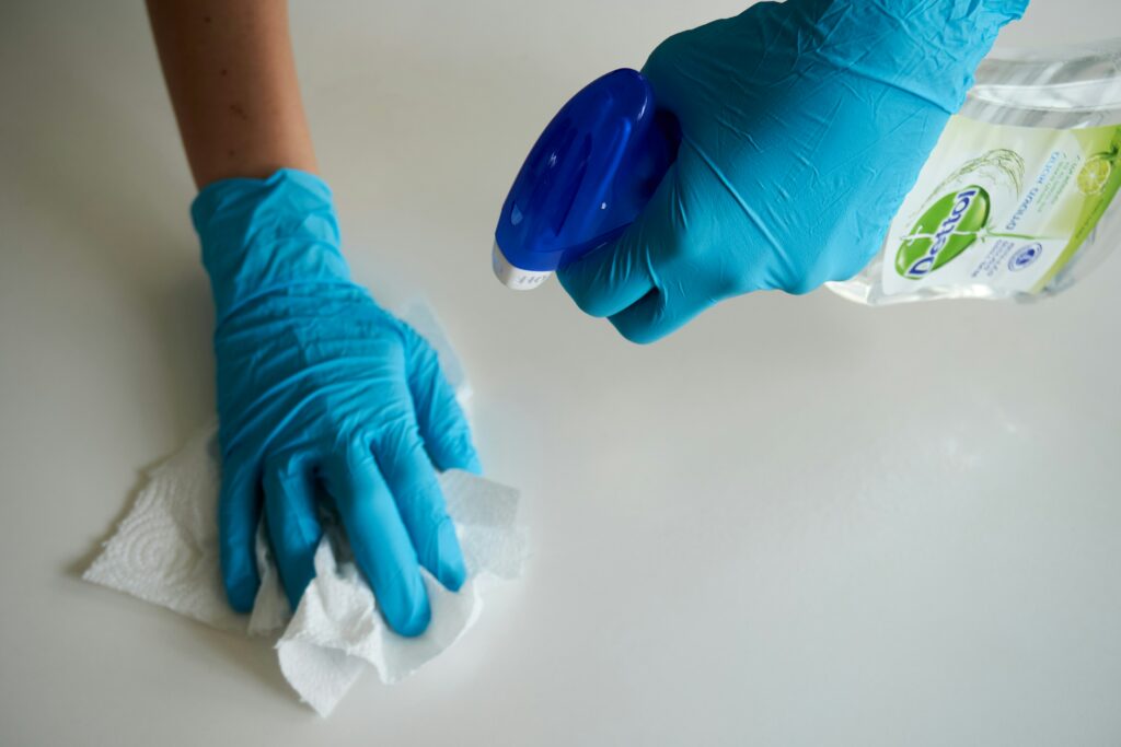 Gloves hands spray and scrub a counter top.