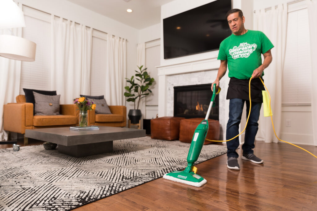 A Naturalcare maid is sweeping floors with a special broom.