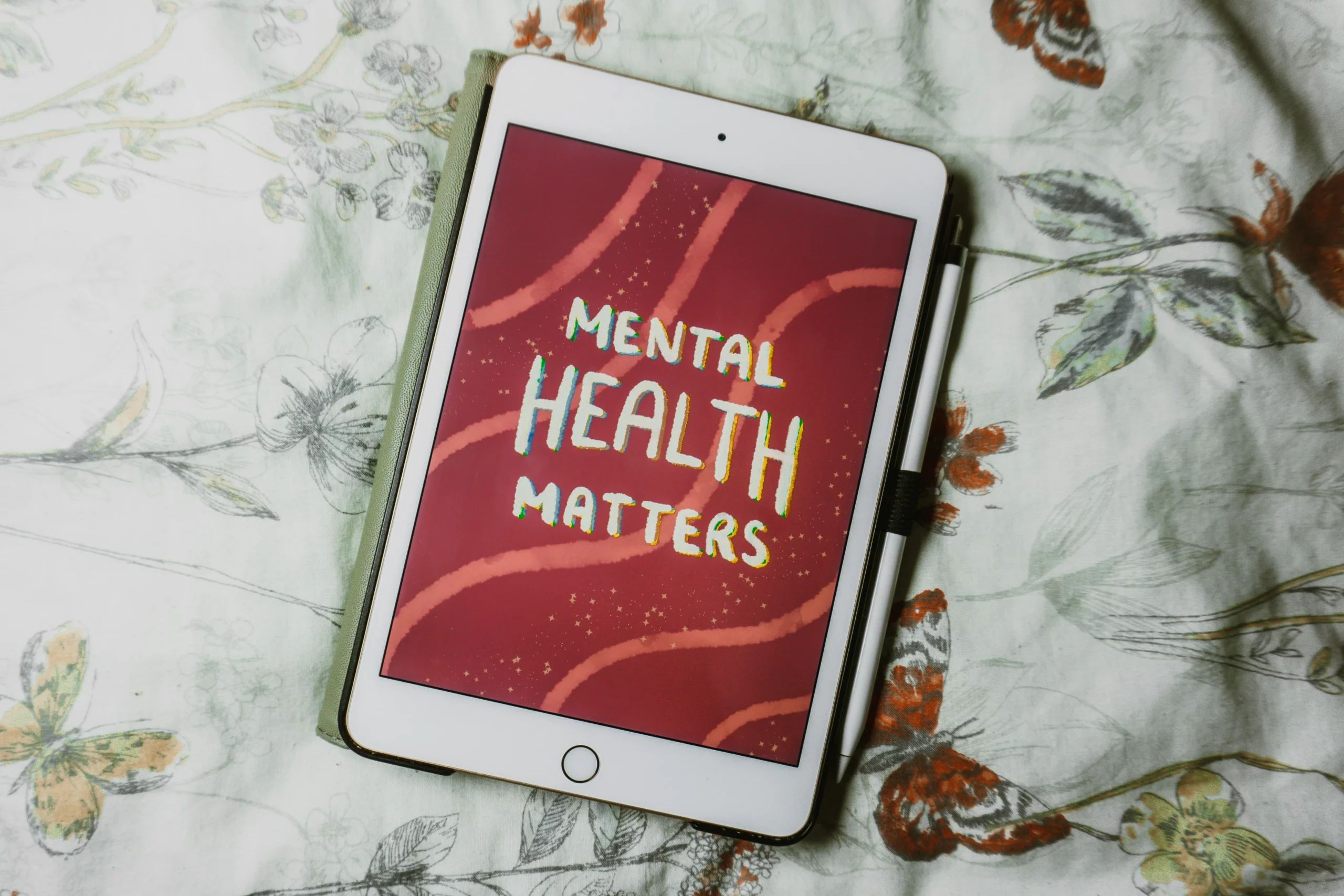 An ipad on a floral bedspread that has a lettering illustration on it, reading 'mental health matters'. ADHD cleaning tips provide support for people living with ADHD.