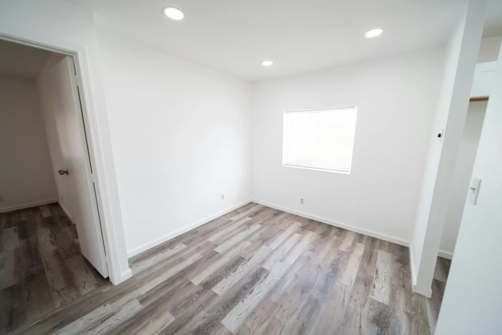 An empty room with grey wood floors and white walls. They have received a move out cleaning service.