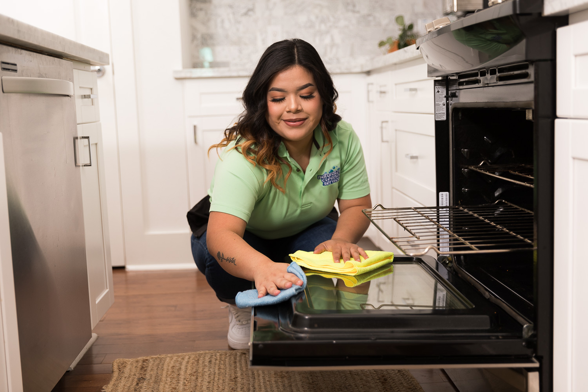 A Naturalcare Pecan Grove cleaner is wiping the inside of an oven down.