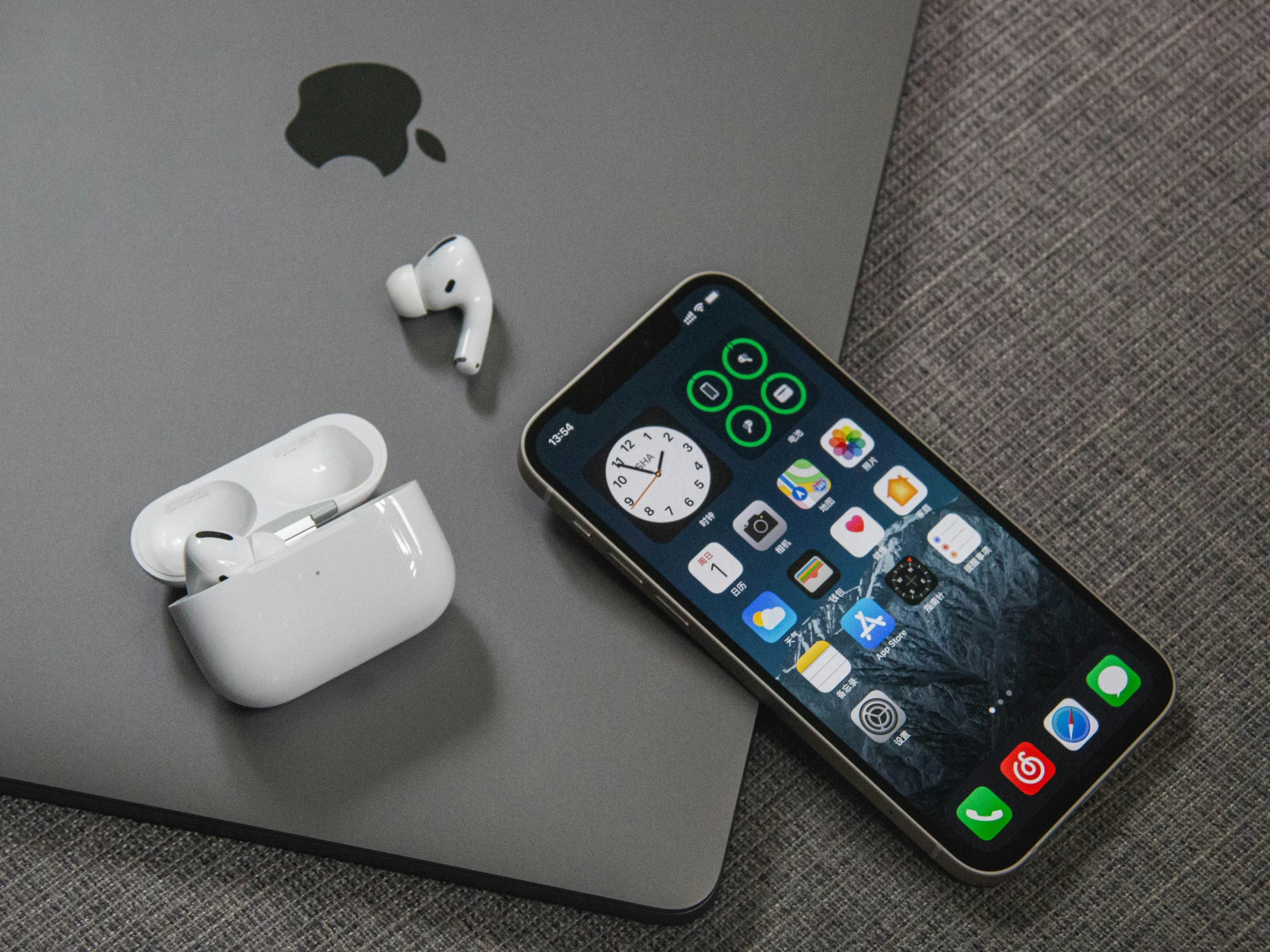 A macbook, iphone, and airpods are on a desk. ADHD cleaning tips suggest they can help minimize distractions if used correctly.
