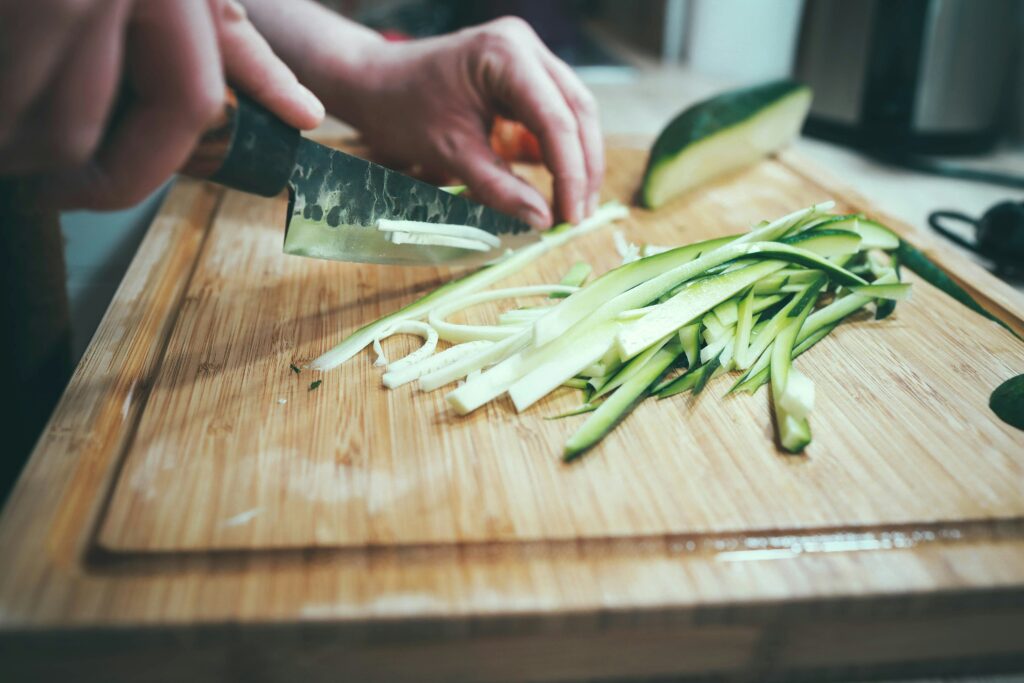 Someone is chopping cucumber on a cutting board. They don't realize there are germs from chicken soaked into the grains of the wood. The cross contamination could kill.