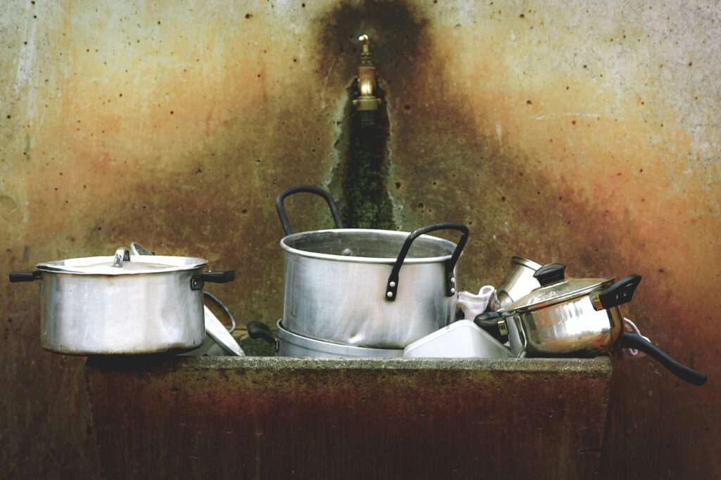 A dingy sink is full of dirty dishes. Kitchen bacteria grows in the kitchen sink faster than anywhere else.